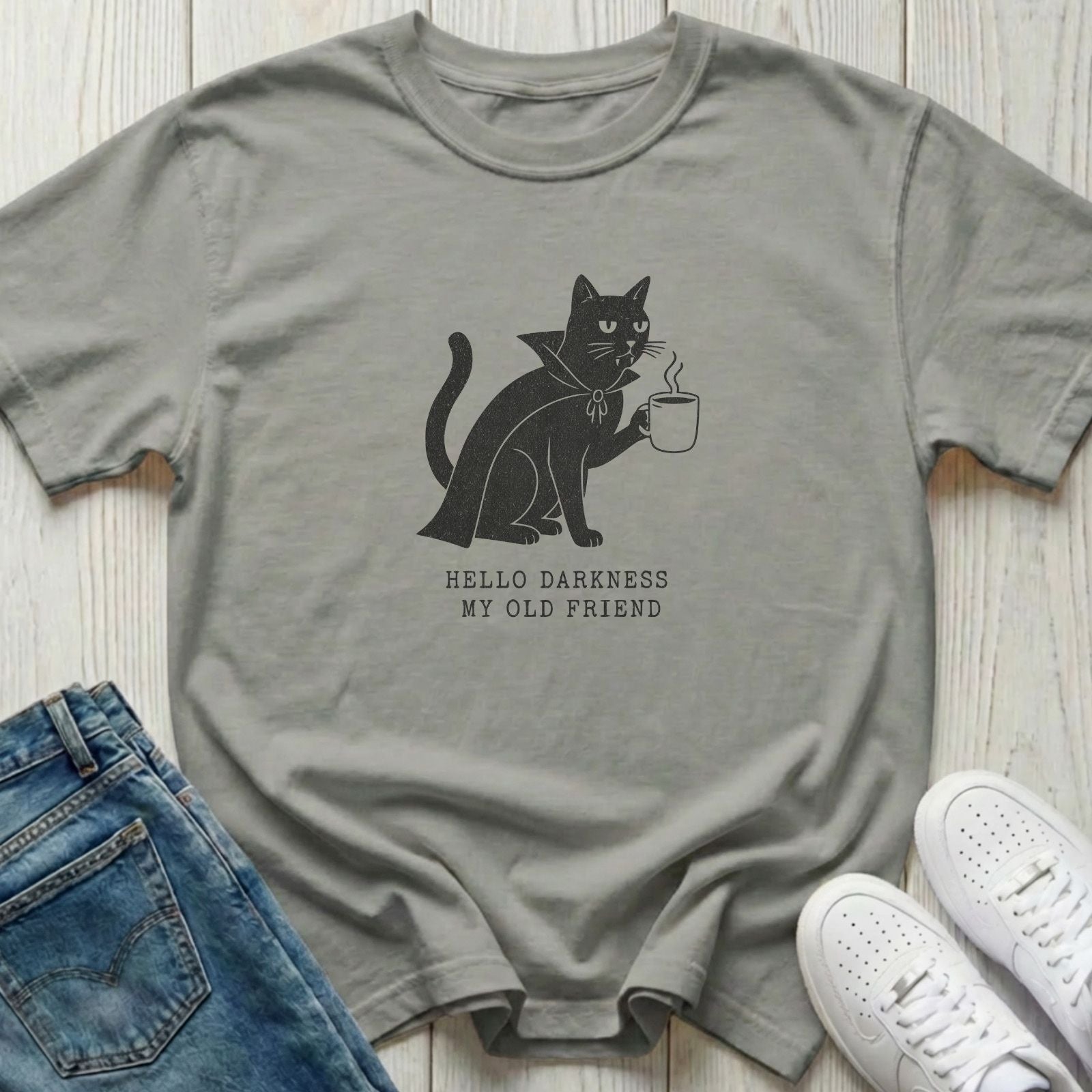 A light gray crewneck t-shirt featuring a black graphic of a cat holding a mug with the text 'HELLO DARKNESS MY OLD FRIEND' underneath. 